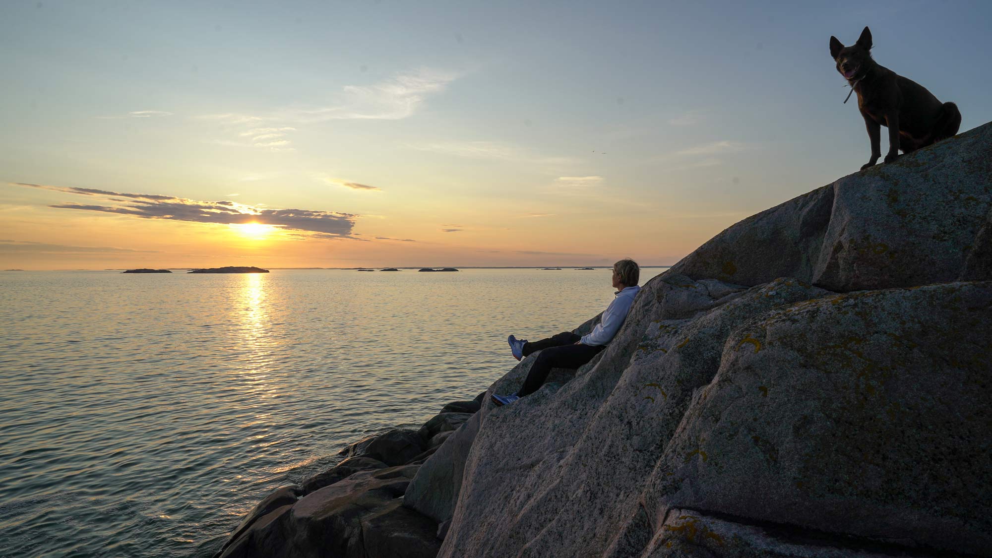 Tee draama jokaisenoikeuksista -tehtävä, koira ja nainen kalliolla auringonlaskun aikaan